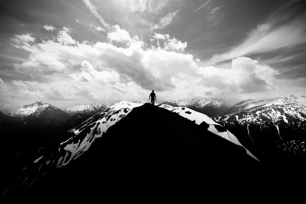Black and white silhouette of a person on mountain range