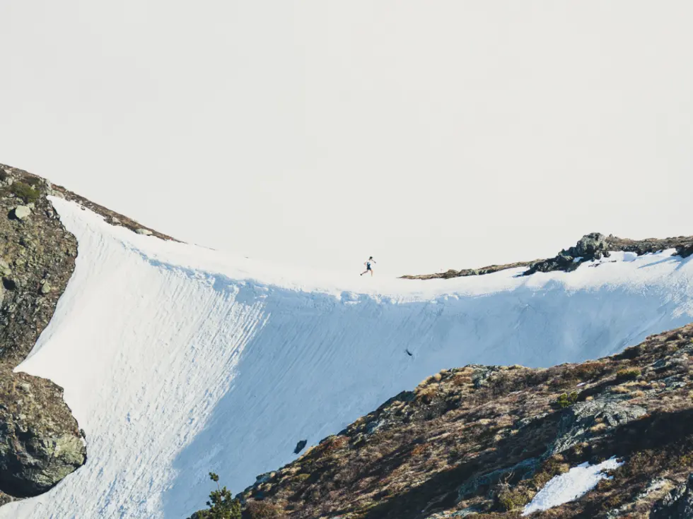 Runner running on snowy cliff at Skyrace Des Matheysins