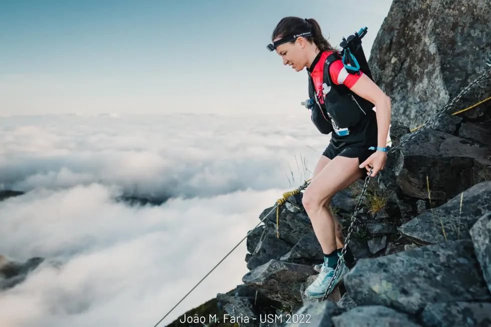 Femal skyrunner on the side of a cliff in the clouds at Hochkonig Skyrace