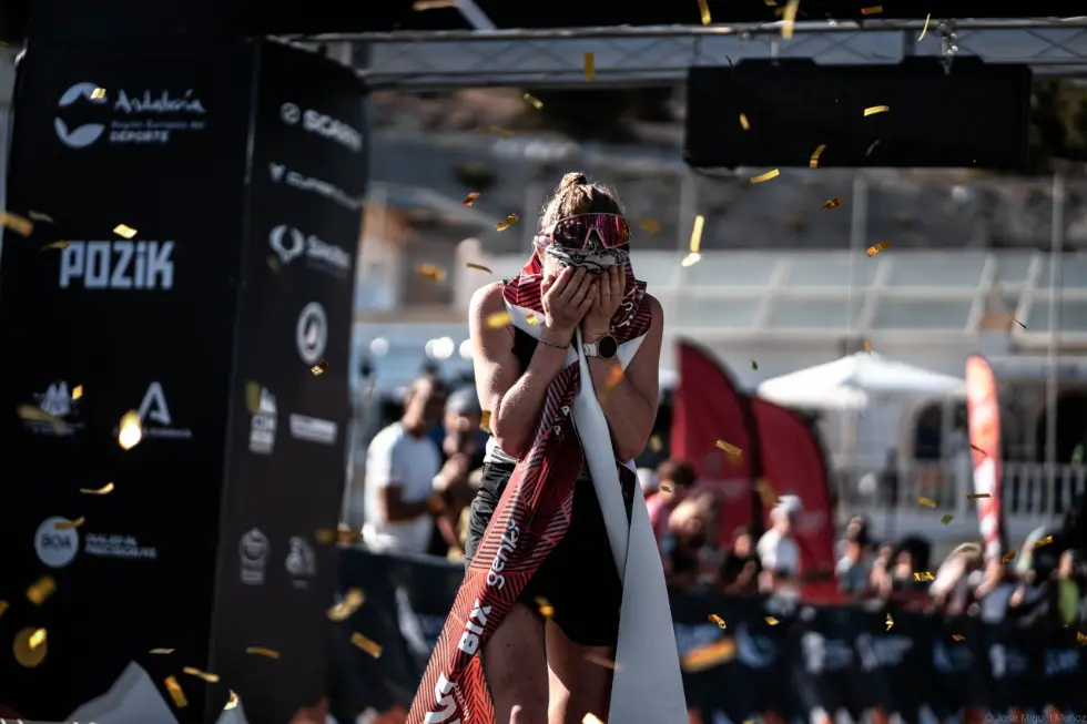 Female Skyrunner Iris Pessey with hands on her face at the finish line