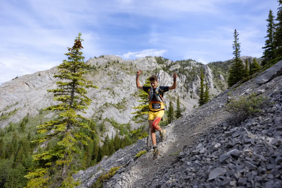 Male skyrunner with arms in the air jumping down part of a trail at Minotaur Skyrace