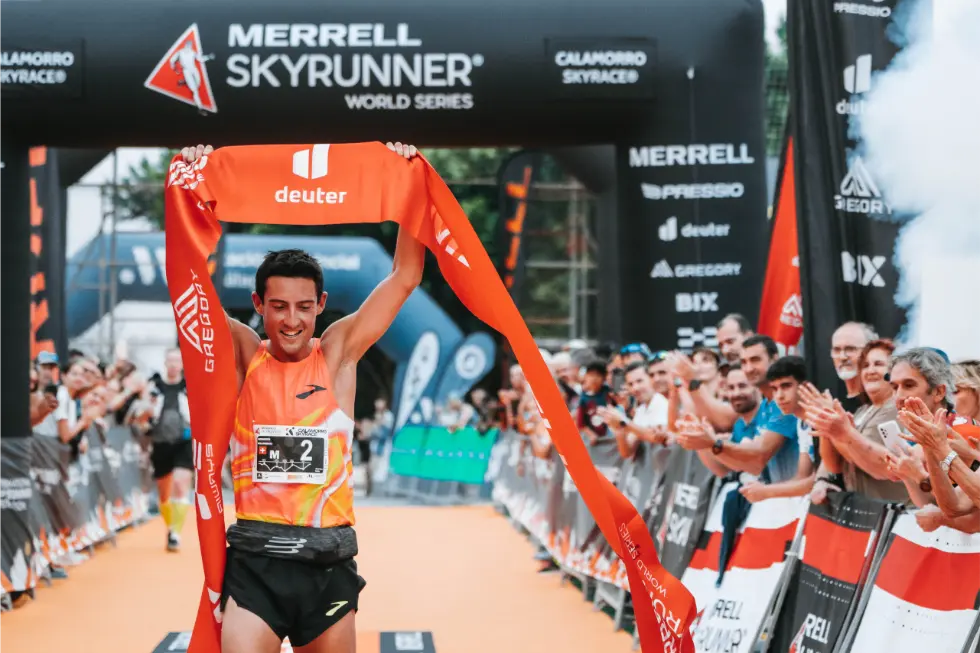 Merrell Skyrunner World Series Calamorro Skyrace Male Athlete holding sponsor banner