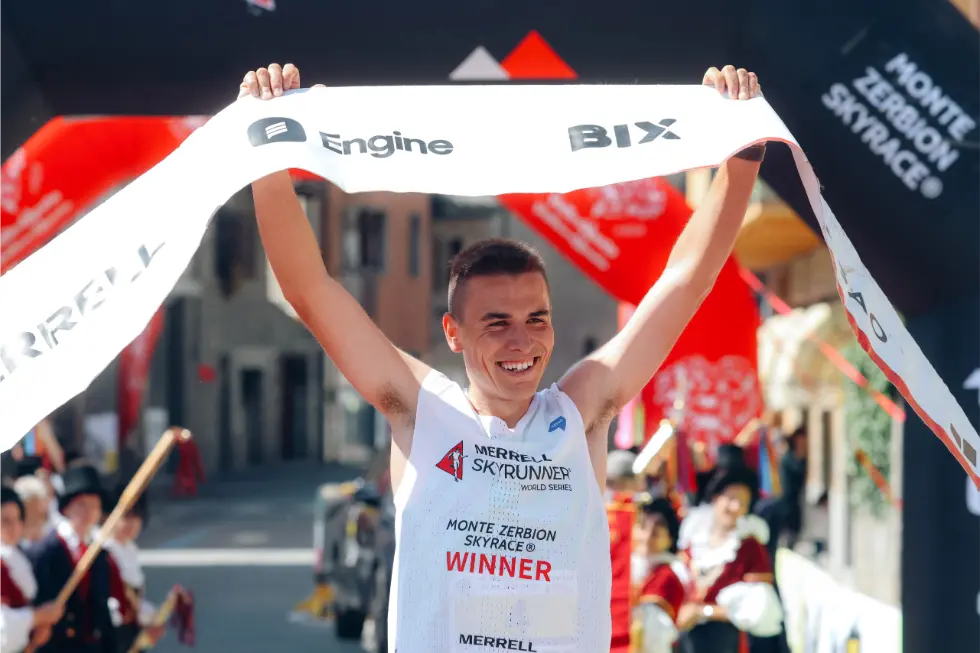Male athlete holding sponsor banner after winning race